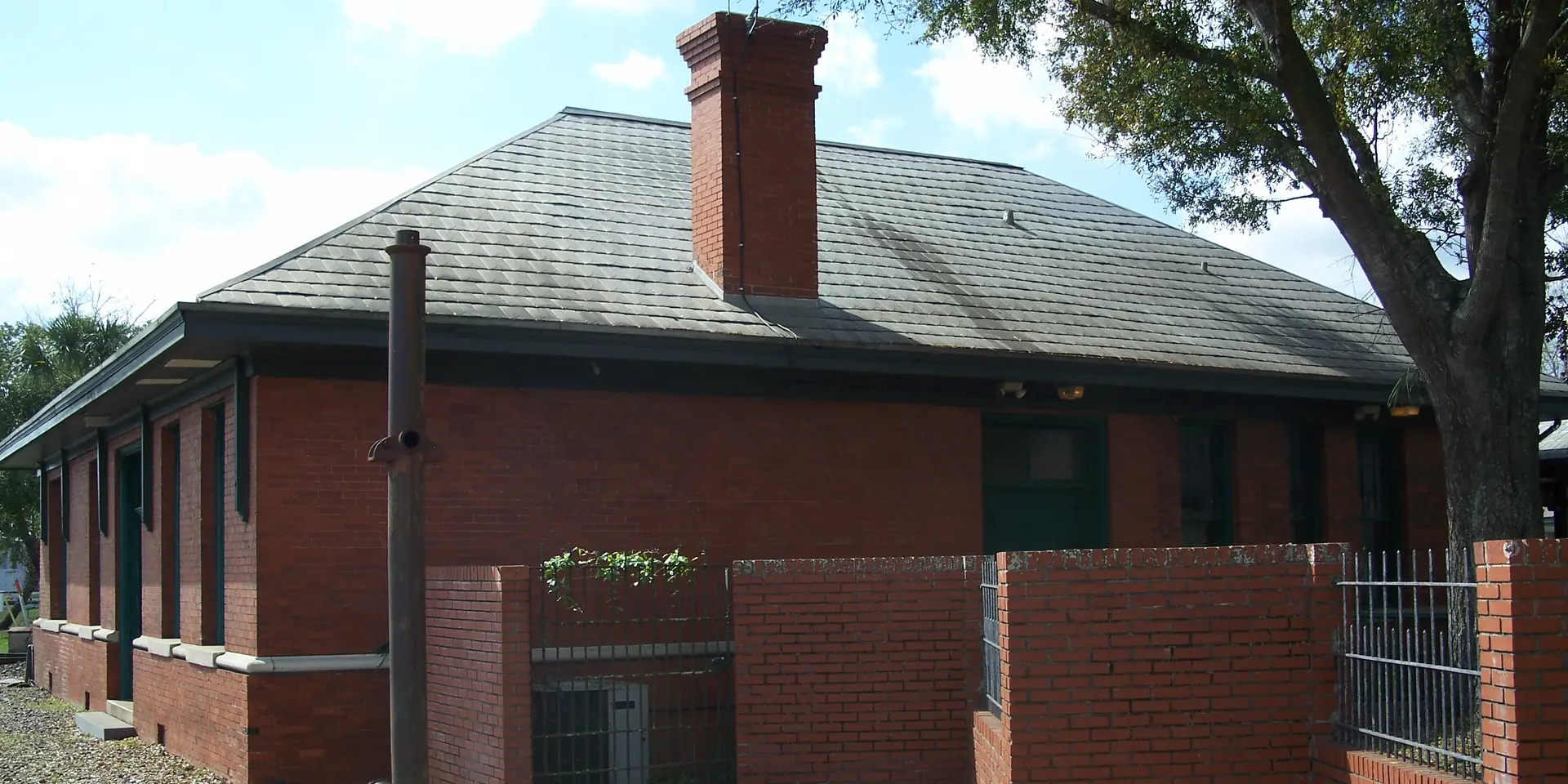 The red brick Union Depot in Plant City, a single-story station with a slate roof and a brick chimney beside an oak